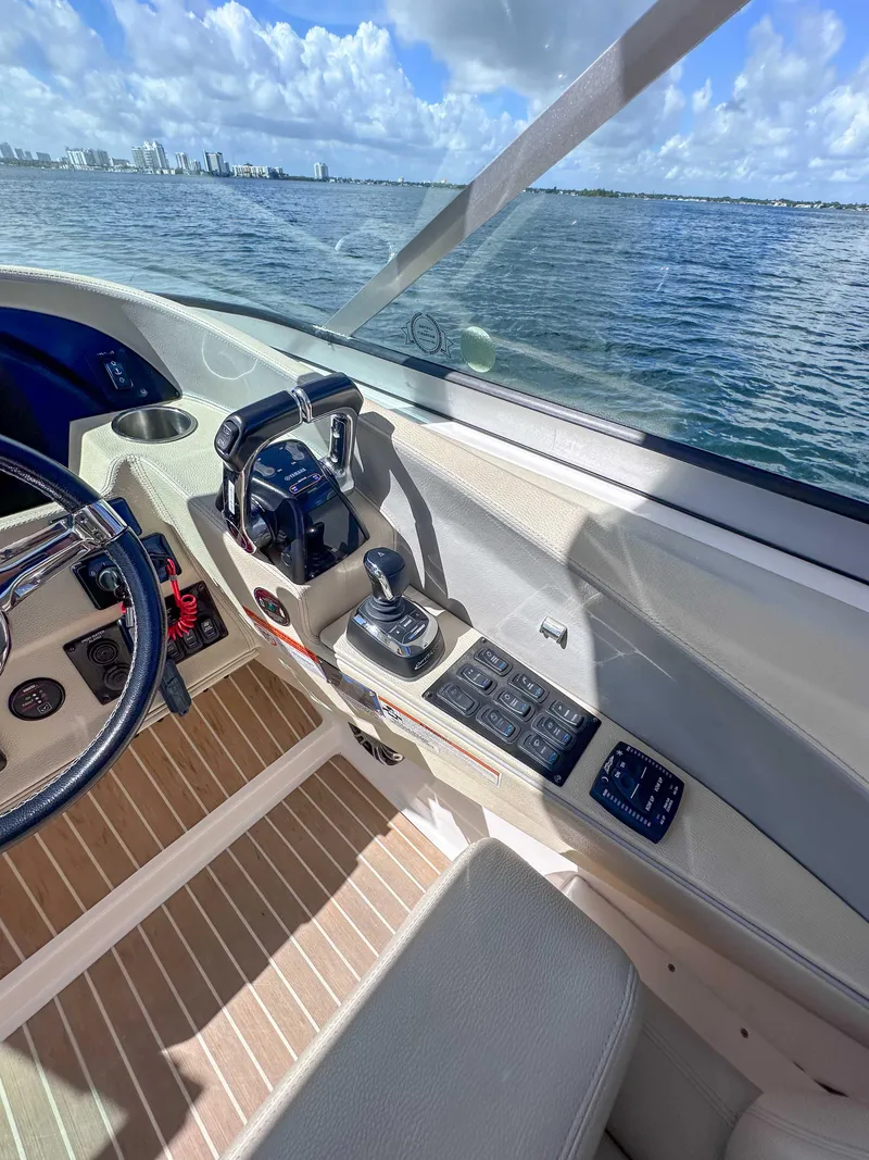 Slide: The Image of 2019 Regal 33 OBX boat cockpit with controls, steering wheel, and ocean view. - 19