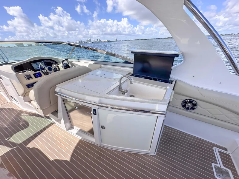 Slide: The Image of 2019 Regal 33 OBX boat interior with helm, sink, and seating on a sunny day. - 25