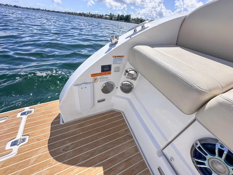 Slide: The Image of 2019 Regal 33 OBX boat with teak deck and cushioned seating by the water. - 32