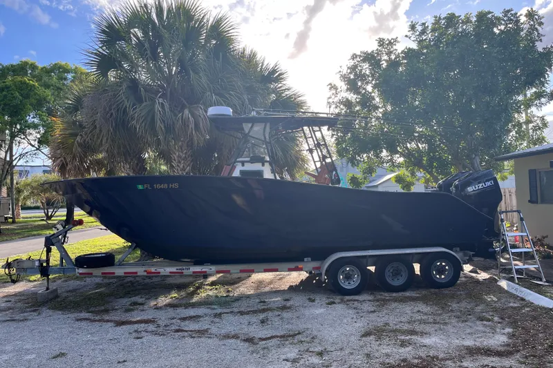 The Image of 1993 Cape Horn 27 boat on trailer, parked outdoors with trees in the background. - 1
