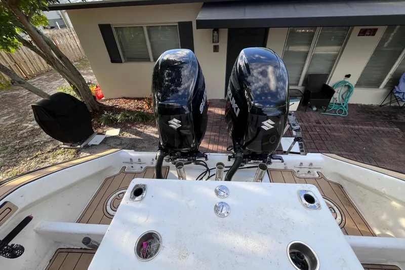 Slide: The Image of Cape Horn 27 boat with dual Suzuki outboard motors, parked near a house. - 12