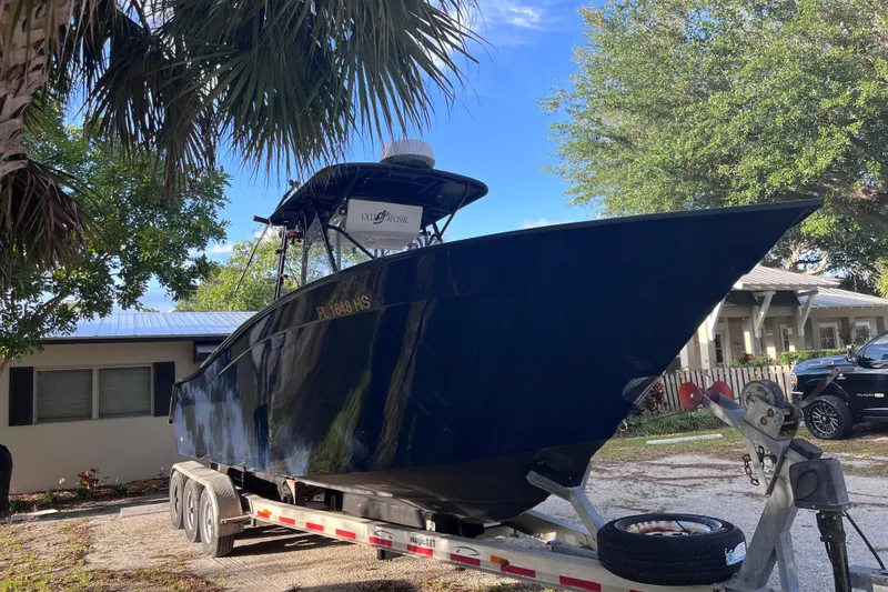 Slide: The Image of 1993 Cape Horn 27 boat on trailer, parked near house with trees in background. - 3