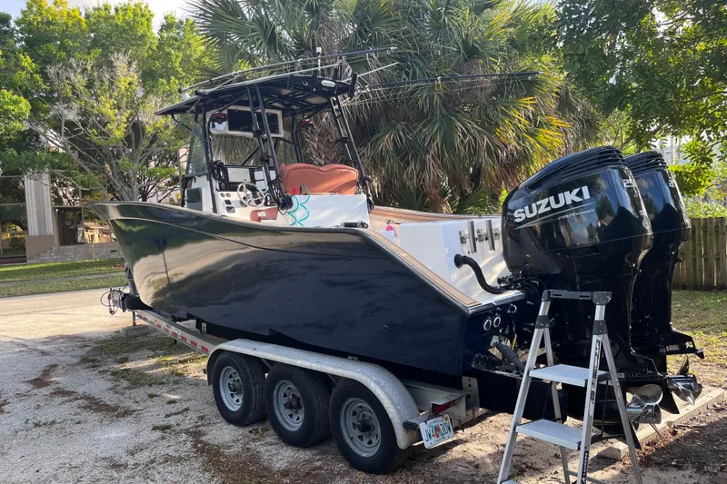 Slide: The Image of 1993 Cape Horn 27 boat on trailer with Suzuki outboard engines, parked near palm trees. - 5