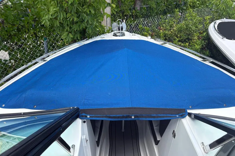 Slide: The Image of 2023 Monterey 255SS Super Sport boat with blue cover, docked near greenery. - 4