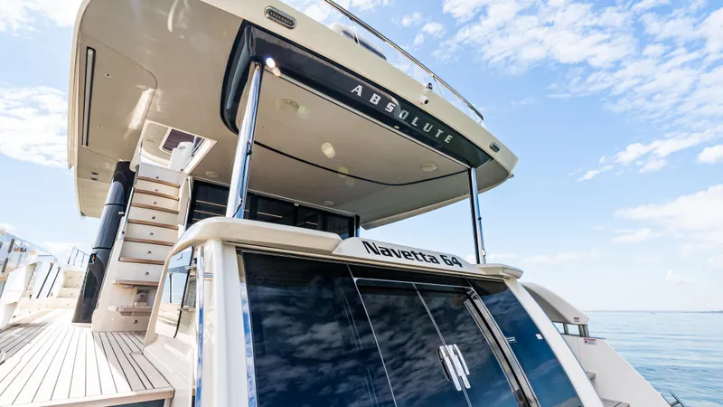 Slide: The Image of 2025 Absolute Navetta 64 yacht, rear view, docked under a clear blue sky. - 10