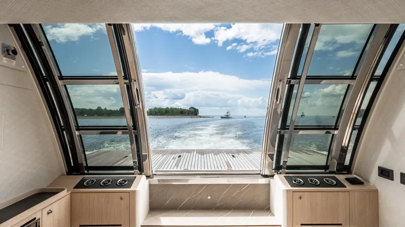 Slide: The Image of Interior view from Absolute Navetta 64 yacht, showcasing panoramic windows and ocean scenery, 2025 model. - 11