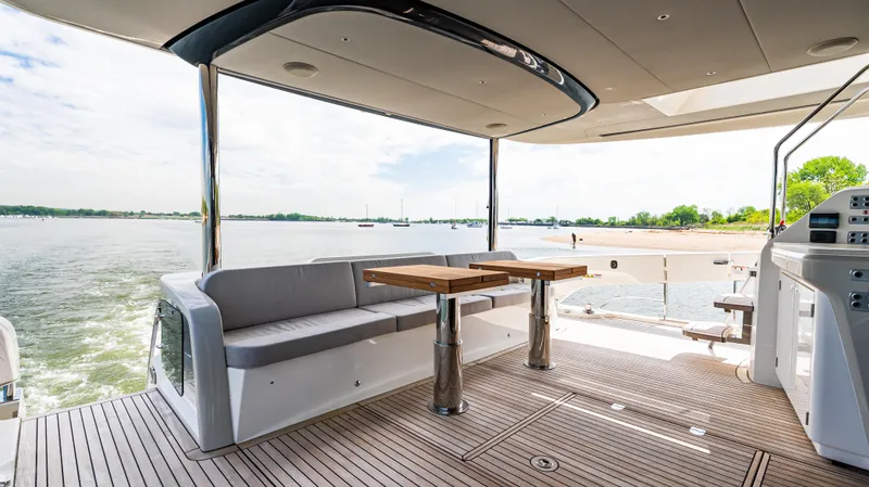 Slide: The Image of Luxurious 2025 Absolute Navetta 64 yacht deck with seating and table, overlooking serene waters. - 17