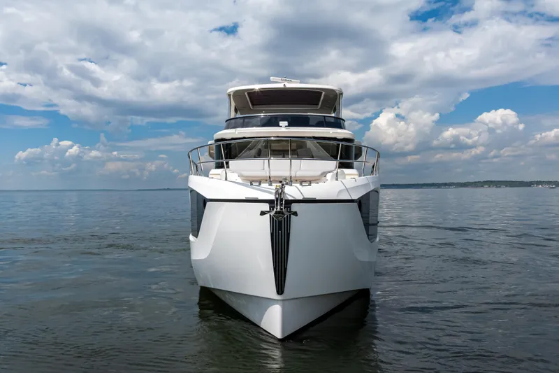 Slide: The Image of 2025 Absolute Navetta 64 yacht on calm water under a partly cloudy sky. - 2