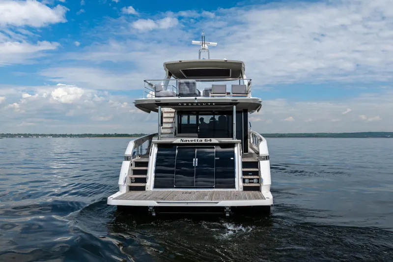 Slide: The Image of 2025 Absolute Navetta 64 yacht on calm water under a partly cloudy sky. - 7