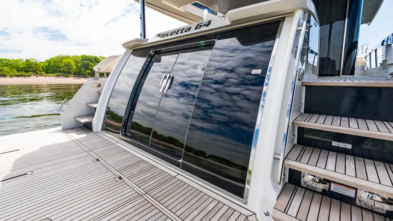Slide: The Image of 2025 Absolute Navetta 64 yacht with sleek design and reflective glass doors. - 9