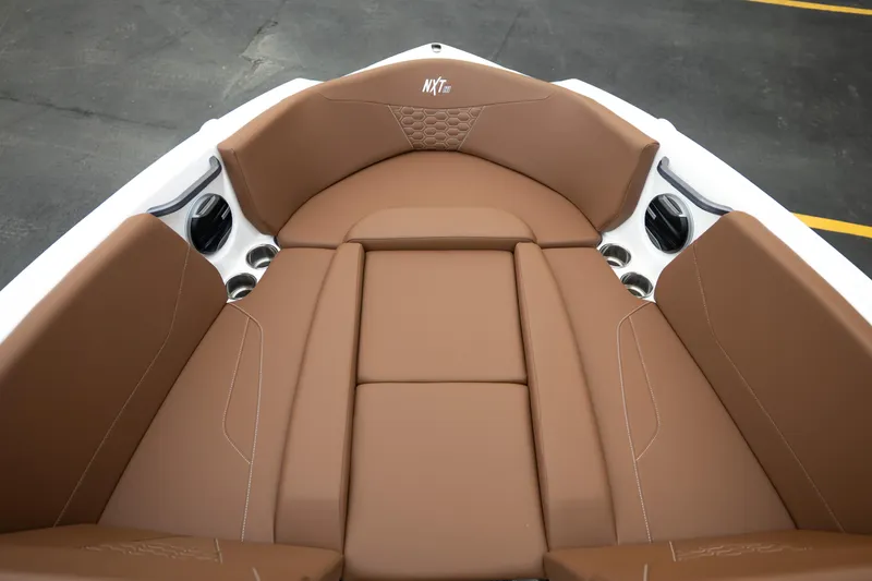 Slide: The Image of 2026 MasterCraft NXT23 boat interior with brown cushioned seating and cup holders. - 21
