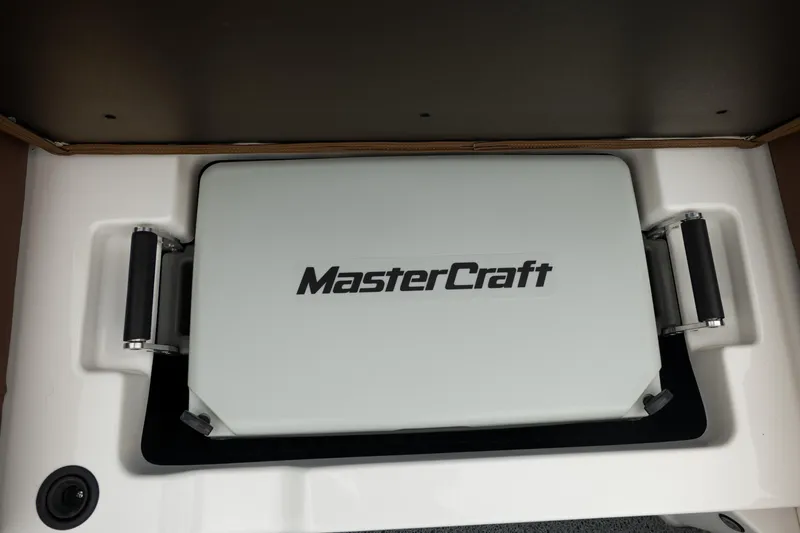 Slide: The Image of 2026 MasterCraft NXT23 boat storage compartment with branded cover. - 25