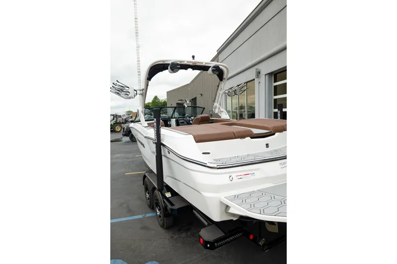Slide: The Image of 2026 MasterCraft NXT23 boat with brown seating, parked outside a building. - 30