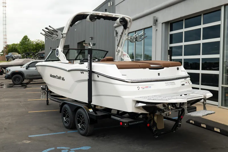 Slide: The Image of 2026 MasterCraft NXT23 boat on trailer, parked outside a building. - 5