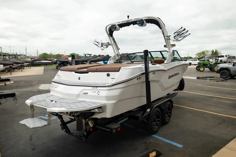 Slide: The Image of 2026 MasterCraft NXT23 boat on trailer, displayed outdoors in a parking lot. - 8