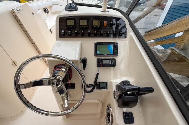 Slide: The Image of 2015 Grady-White Freedom 275 boat dashboard with steering wheel and navigation controls. - 18