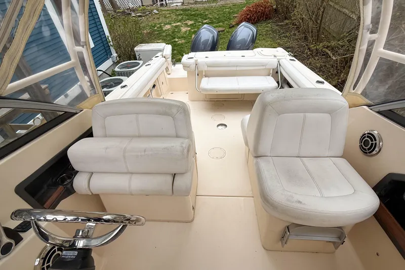 Slide: The Image of 2015 Grady-White Freedom 275 boat interior with white seating and steering wheel. - 33
