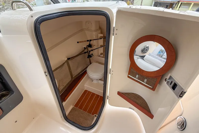 Slide: The Image of 2015 Grady-White Freedom 275 boat interior with compact bathroom and fishing rod storage. - 22