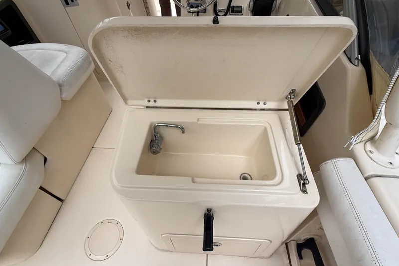 Slide: The Image of Open storage compartment with faucet on 2015 Grady-White Freedom 275 boat interior. - 39