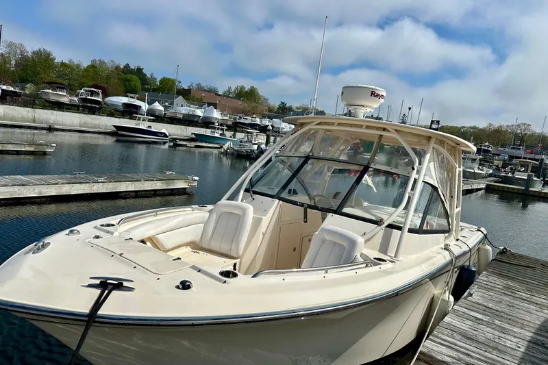 Slide: The Image of 2015 Grady-White Freedom 275 boat docked at a marina under a cloudy sky. - 3