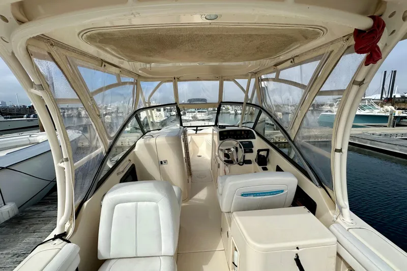 Slide: The Image of 2015 Grady-White Freedom 275 boat interior at marina, featuring helm and seating. - 9