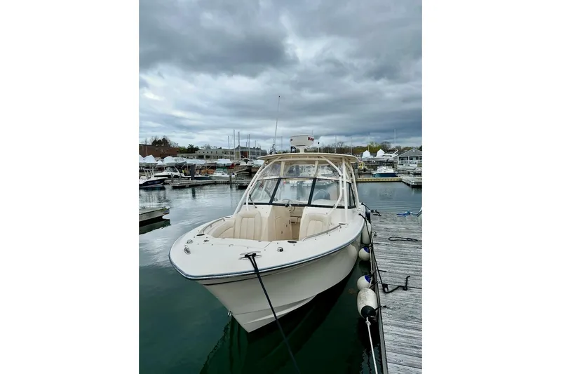 Slide: The Image of 2015 Grady-White Freedom 275 boat docked at marina under cloudy skies. - 2