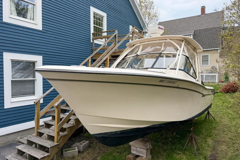 Slide: The Image of 2015 Grady-White Freedom 275 boat on stands beside a blue house. - 12