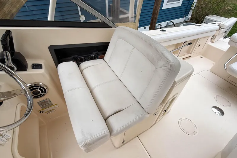 Slide: The Image of 2015 Grady-White Freedom 275 boat interior with white seating and steering wheel. - 17