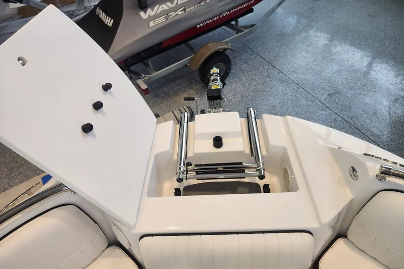 Slide: The Image of 2026 Stingray 211 DC boat interior with open storage compartment and chrome fittings. - 13