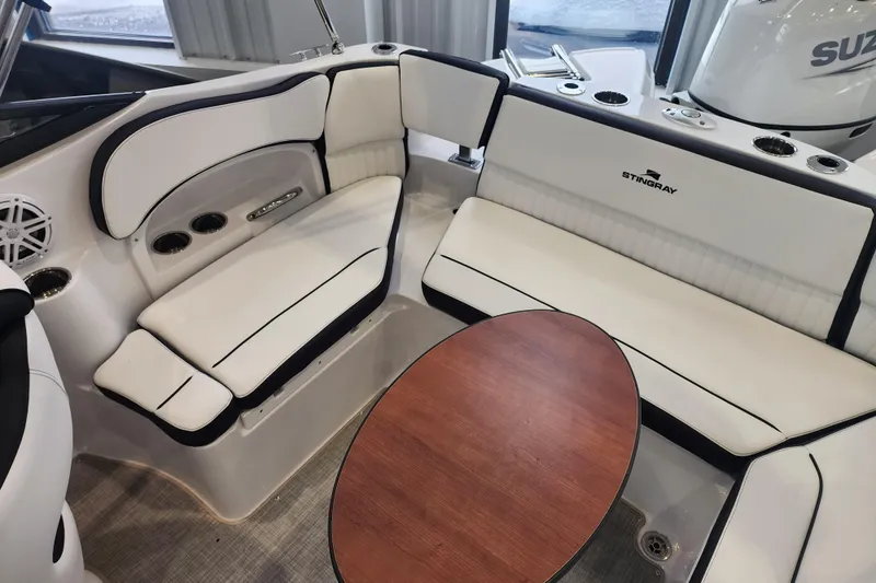Slide: The Image of 2026 Stingray 211 DC boat interior with white seating and wooden table. - 19