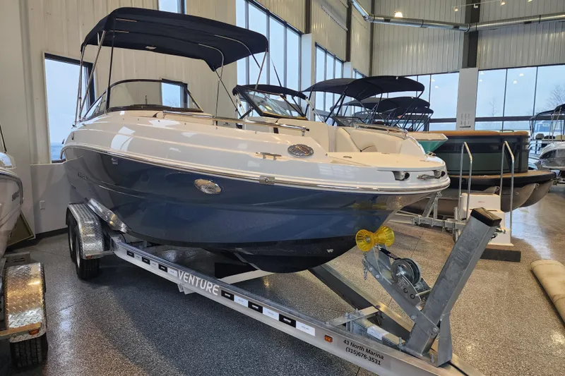 Slide: The Image of 2026 Stingray 211 DC boat on trailer in showroom, featuring sleek design and blue hull. - 2