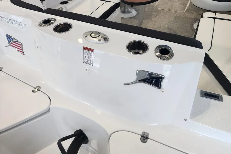 Slide: The Image of 2026 Stingray 211 DC boat interior with cup holders and American flag emblem. - 31
