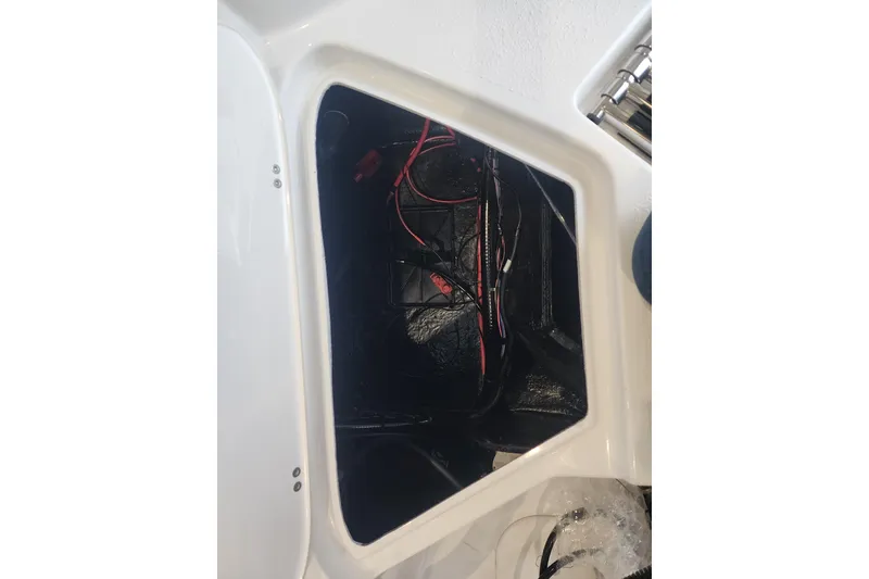Slide: The Image of Open compartment of 2026 Stingray 211 DC boat showing wiring and storage space. - 32