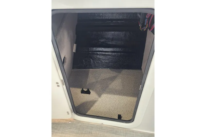 Slide: The Image of Interior storage compartment of 2026 Stingray 211 DC boat, featuring carpeted flooring. - 38