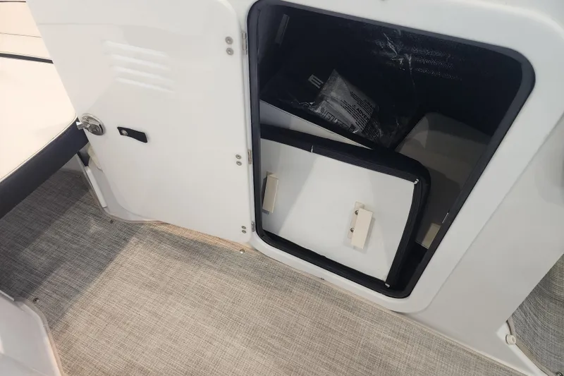 Slide: The Image of Open storage compartment on 2026 Stingray 211 DC boat, featuring carpeted flooring. - 47