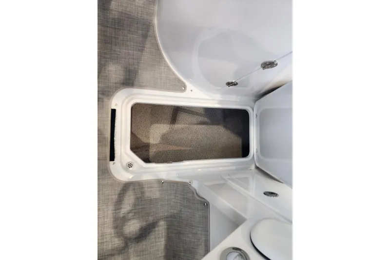 Slide: The Image of Interior storage compartment of 2026 Stingray 211 DC boat, featuring carpeted flooring. - 48