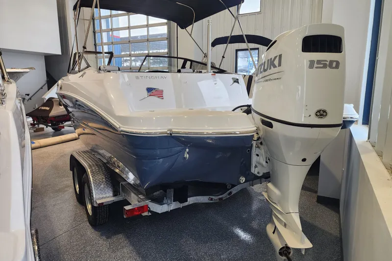 Slide: The Image of 2026 Stingray 211 DC boat with Suzuki 150 outboard motor in showroom. - 5