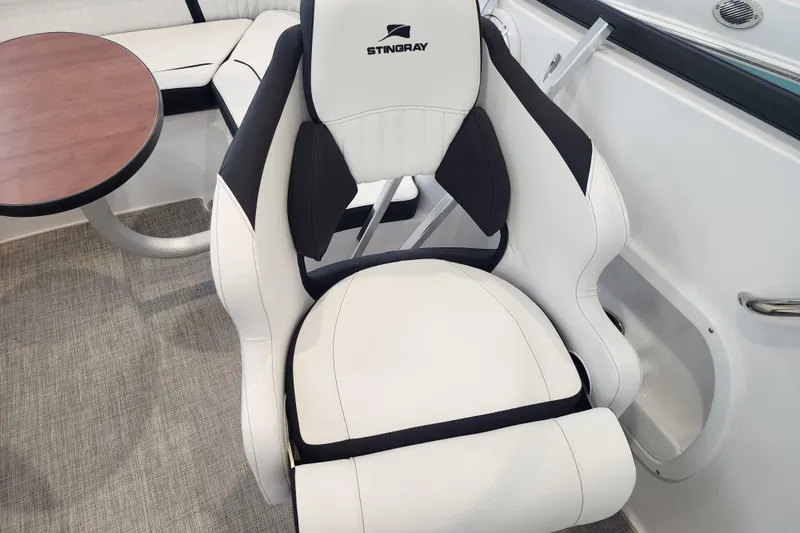 Slide: The Image of 2026 Stingray 211 DC boat interior with white and black seating and a round table. - 51