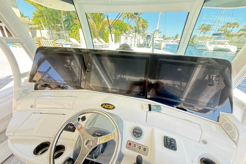 Slide: The Image of 2019 HCB 53 Suenos helm with multiple screens and steering wheel, docked by a marina. - 18