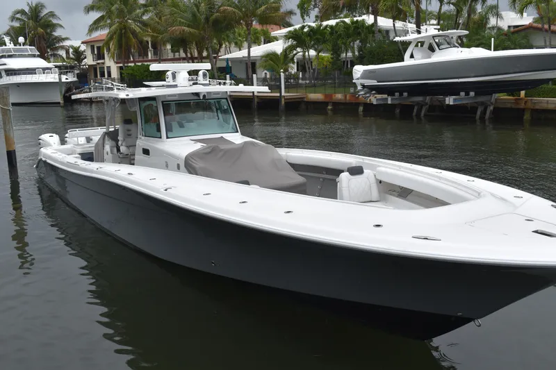 Slide: The Image of 2019 HCB 53 Suenos boat docked in a marina, surrounded by palm trees. - 2