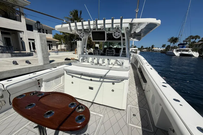Slide: The Image of 2019 HCB 53 Suenos boat interior with fishing rod holders and seating, docked by waterfront homes. - 32