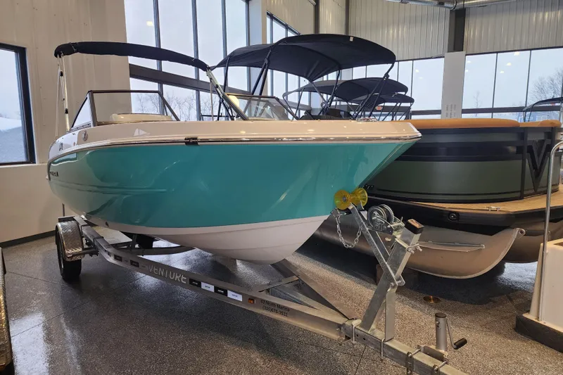 The Image of 2026 Stingray 172 DC boat in showroom, teal hull, on trailer, indoor display. - 0