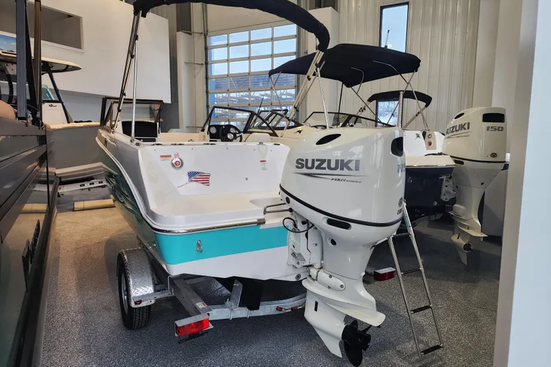 Slide: The Image of 2026 Stingray 172 DC boat with Suzuki outboard motor in showroom. - 2