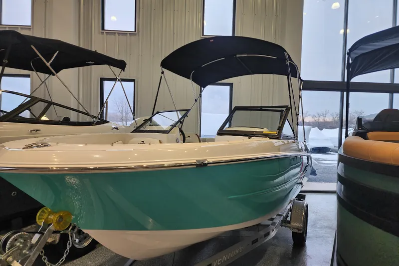 Slide: The Image of 2026 Stingray 172 DC boat displayed indoors with teal hull and black canopy. - 4