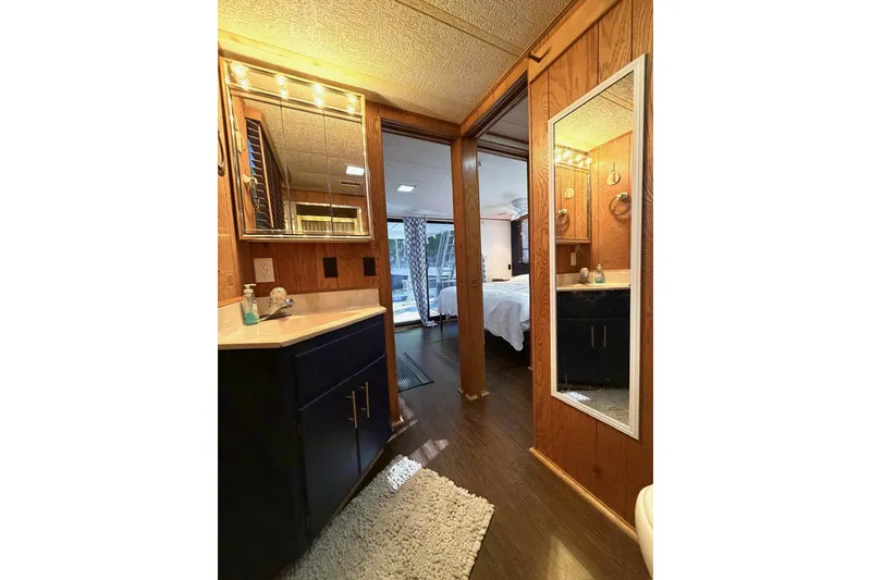 Slide: The Image of 1989 Sumerset 14x63 houseboat interior with wood paneling, bathroom vanity, and bedroom view. - 17