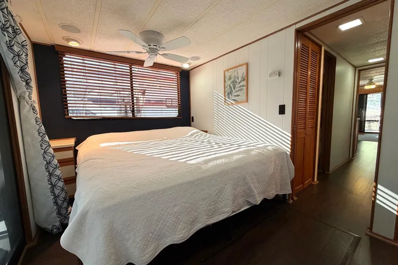 Slide: The Image of Bedroom interior of 1989 Sumerset 14x63 houseboat with large bed, wooden blinds, and ceiling fan. - 19