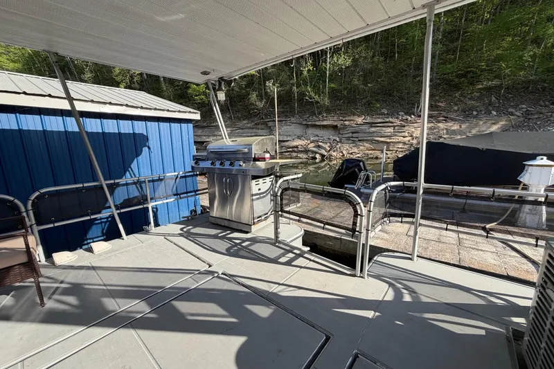 Slide: The Image of Outdoor deck of 1989 Sumerset 14x63 houseboat with grill, docked by rocky shoreline. - 23