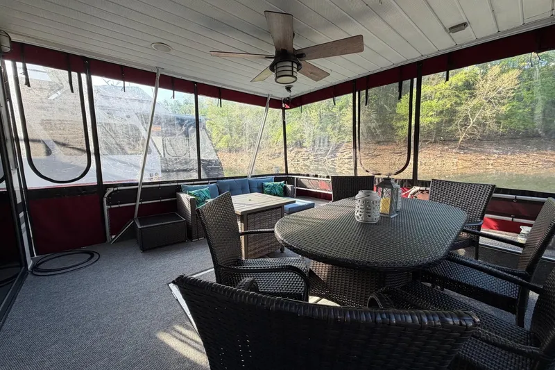 Slide: The Image of Enclosed deck of 1989 Sumerset 14x63 houseboat with wicker furniture and scenic lake view. - 3