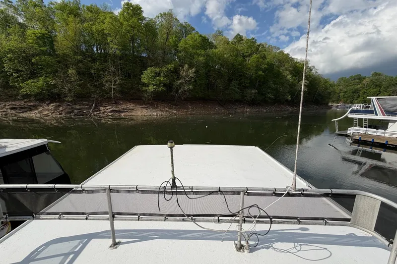 Slide: The Image of 1989 Sumerset 14x63 houseboat docked on a serene lake with lush green trees. - 30