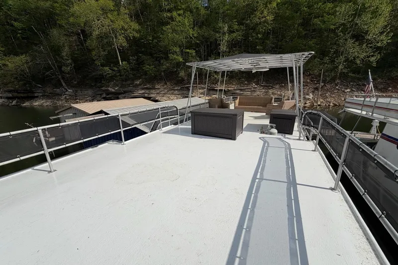Slide: The Image of Rooftop deck of 1989 Sumerset 14x63 houseboat with outdoor seating, surrounded by lush greenery. - 32